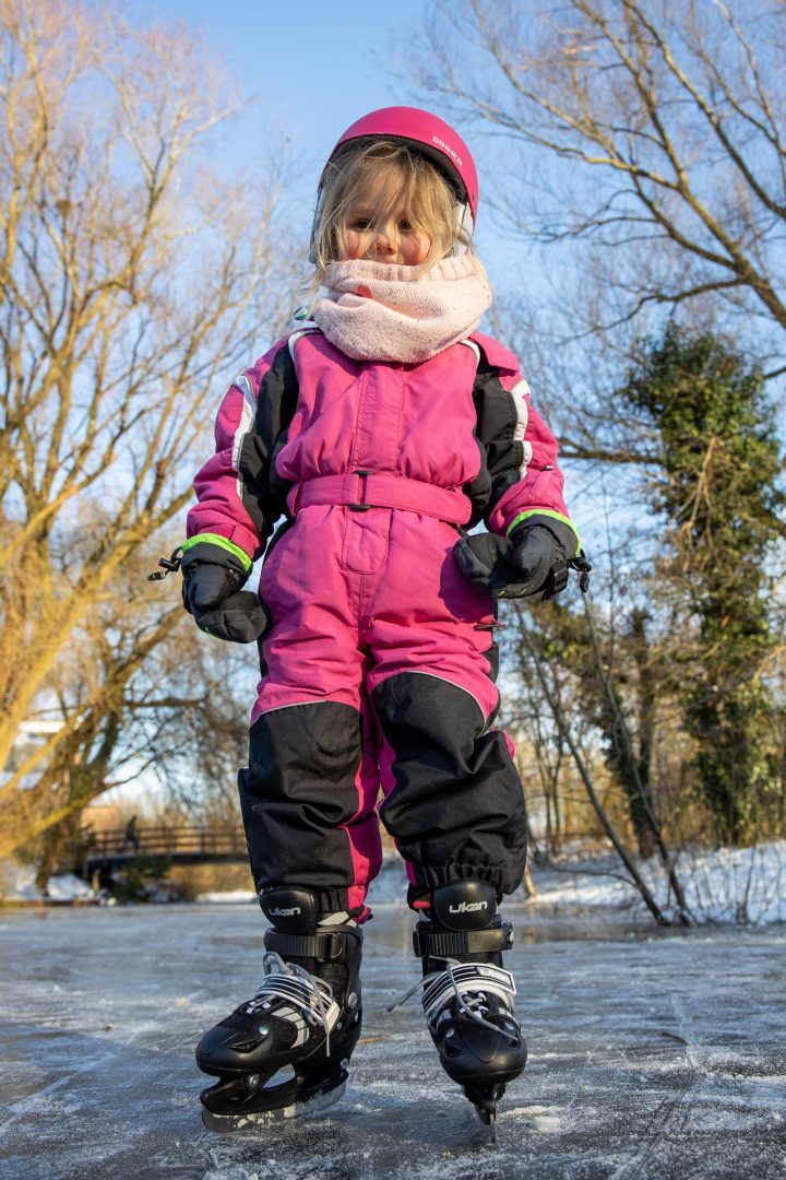 ijspret in Houten, meisje in kleurrijke winterkleding, blozende wangen
